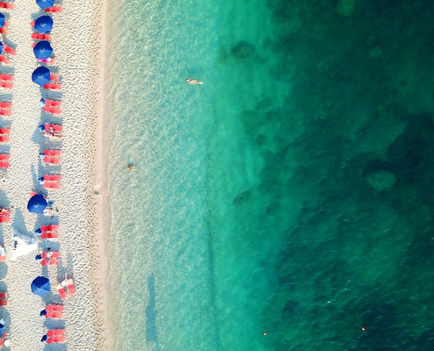 Asaya-Hills-Villas-Parga-Greece-sea-beach-umbrellas-holidays Aerial shot of a sand beach with umbrellas and stunning turquoise waters at Parga, Greece.