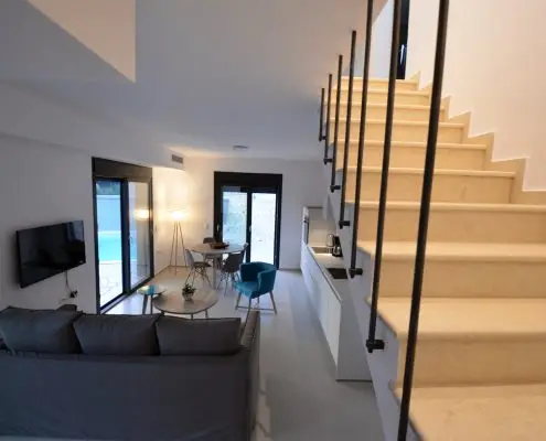 Living room and kitchen with modern furniture and a staircase leading to the upper floor of a private villa at Parga, Greece.
