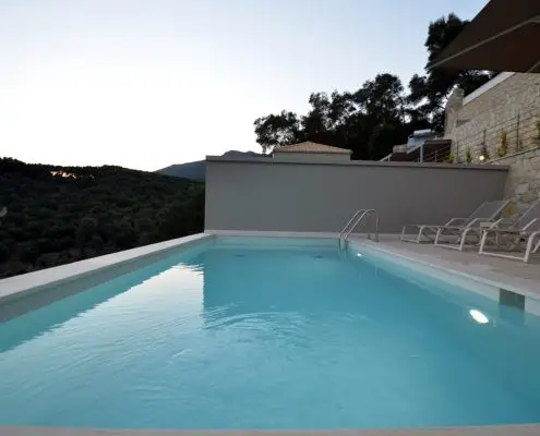 A swimming pool with sunbeds at the exterior space of a private villa at Parga, Greece.